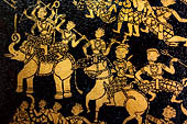 Wat Xieng Thong temple in Luang Prabang, Laos. Detail of the  intricate gold stencilling on black lacquer that decorate the walls of the sim. Detail of the 'battle of Mara' from Buddhist Jataka